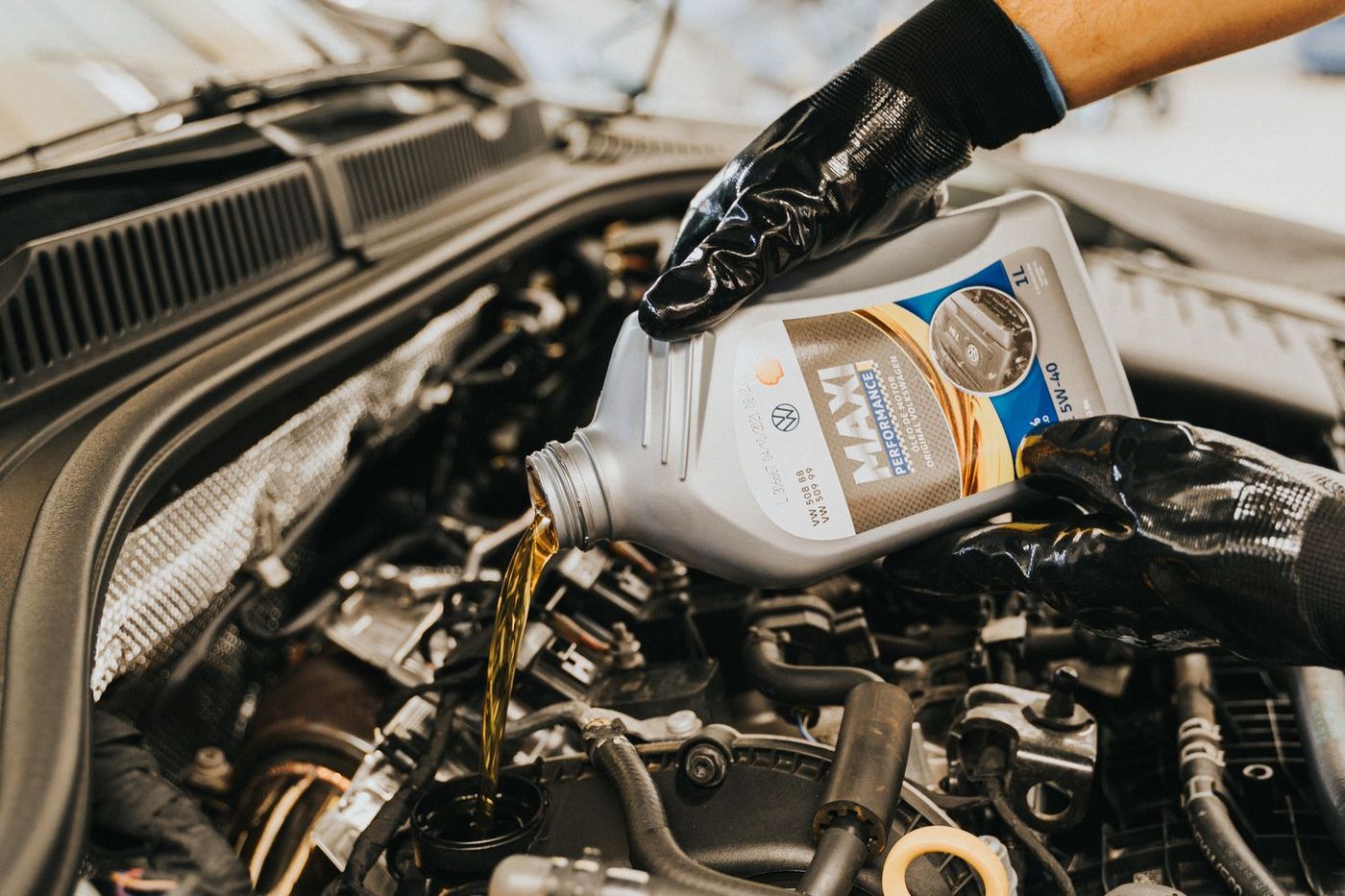 Mecánico vertiendo aceite nuevo en el motor de un auto